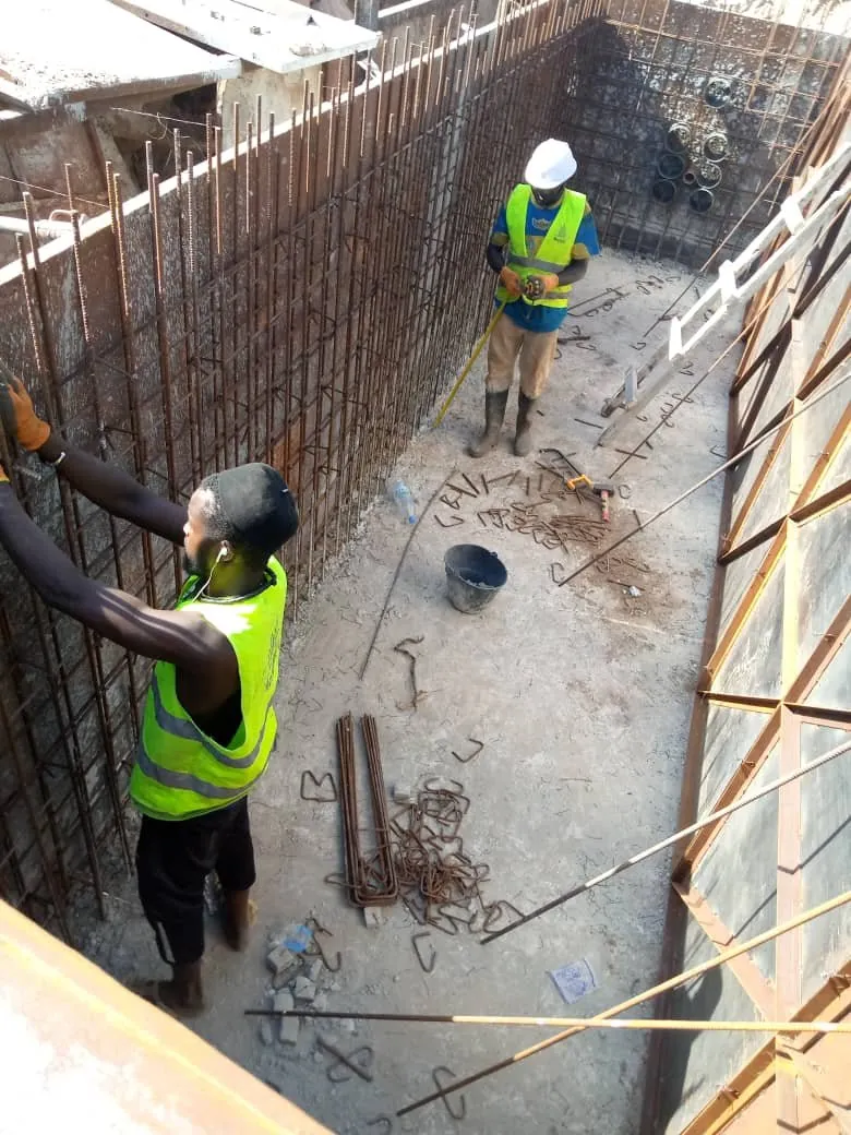 Deux ouvriers dans une fouille blindée avec ferraillage vertical d'un regard en béton armé