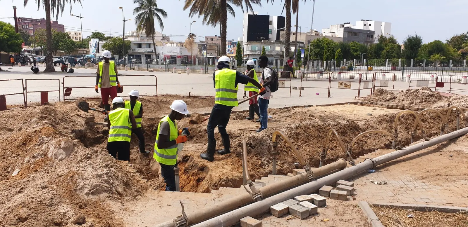 Équipe en gilets jaunes creusant une fouille pour la pose de conduites en milieu urbain