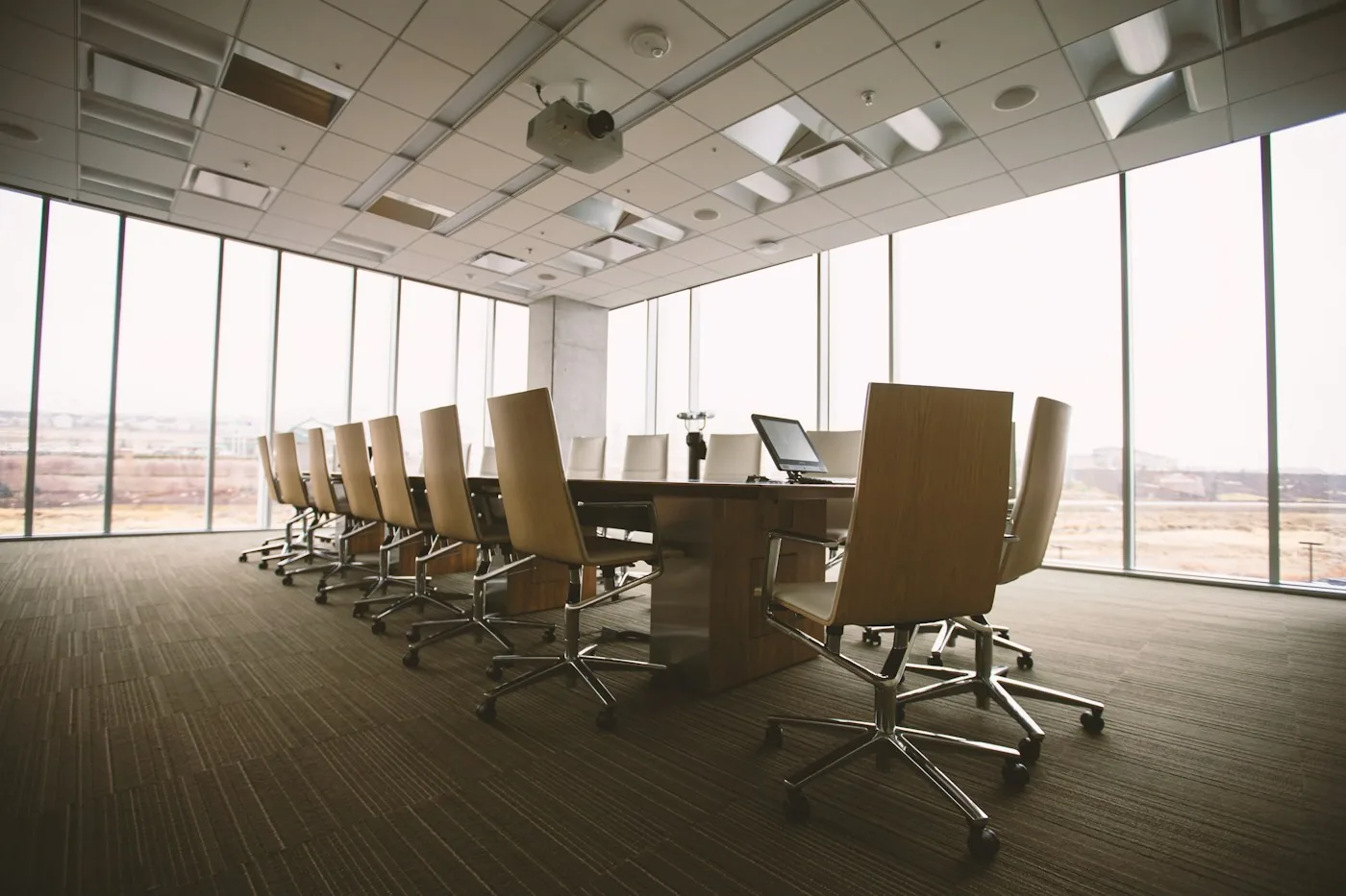 Salle de conseil vitrée avec grande table de réunion en bois