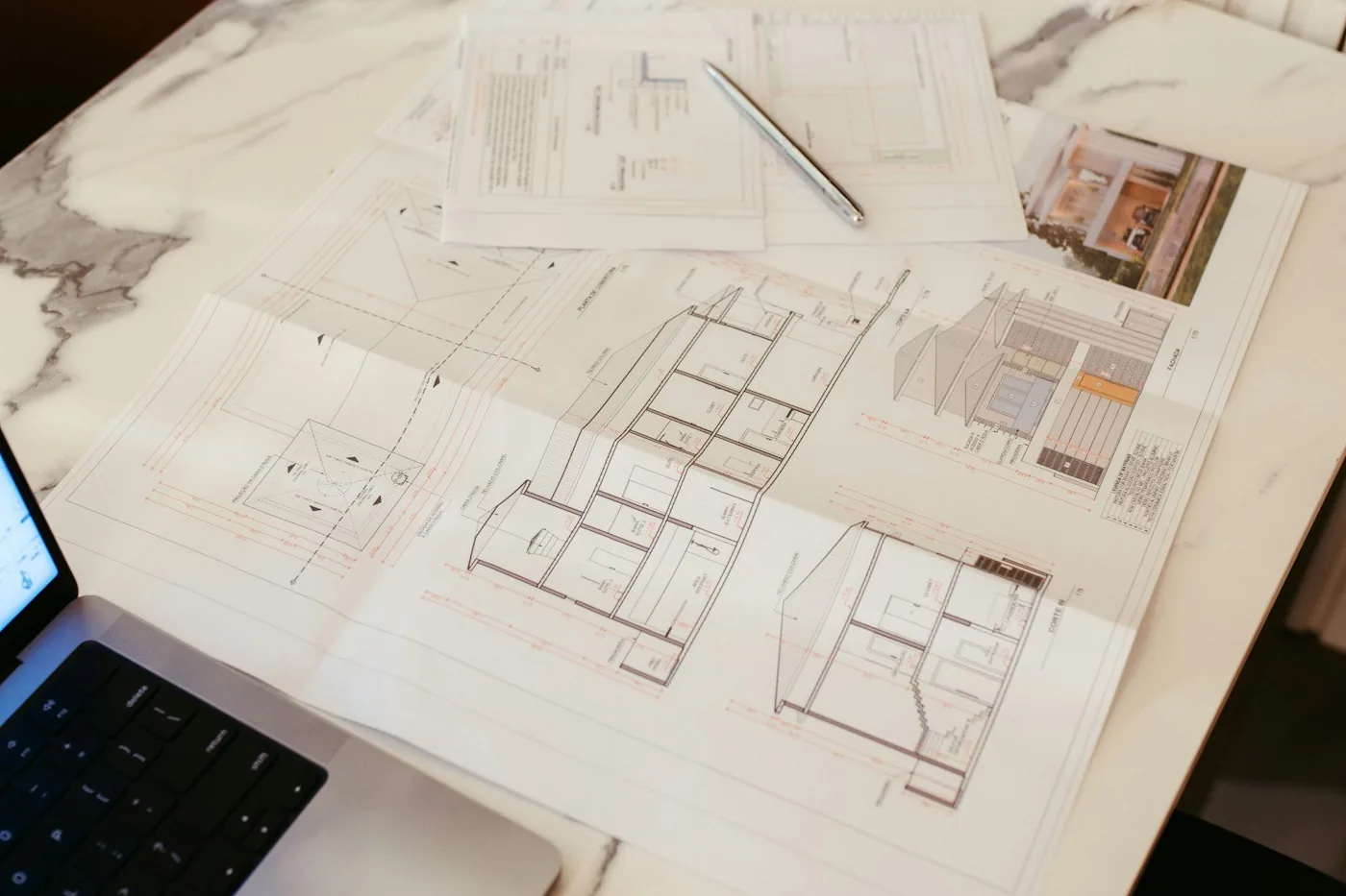 Plans d'architecte étalés sur un bureau à côté d'un ordinateur portable